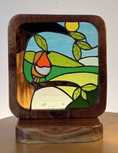 Stained glass and wood robin on a tree branch