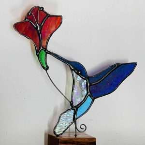 Stained Glass iridescent hummingbird and a red flower on a wooden base